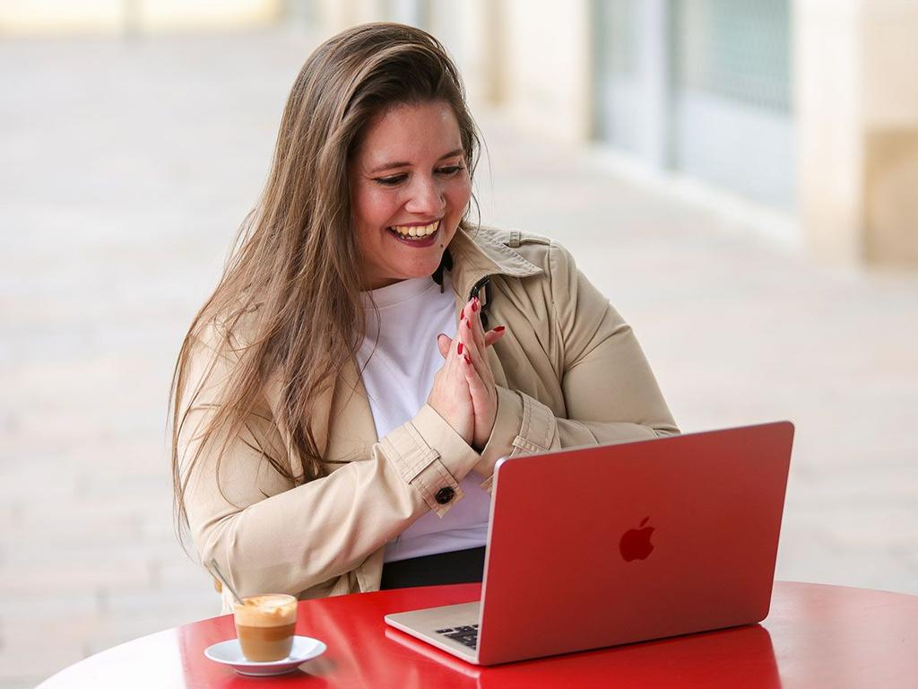 Johanna Juha sonriendo frente a su portátil en una terraza
